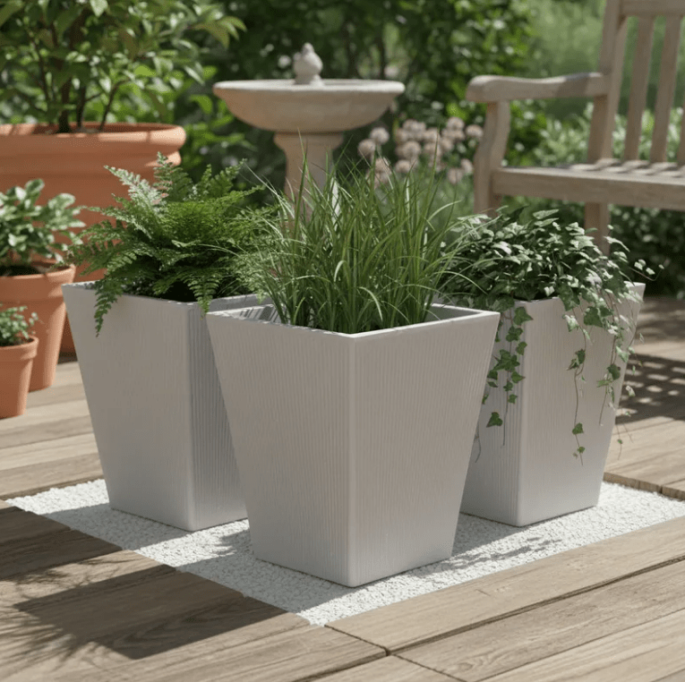 Macetero Venus 55 TERA Italy color Gris Claro — tres macetas con helecho, pasto ornamental y hiedra, sobre deck de madera junto a fuente de agua — bCasual