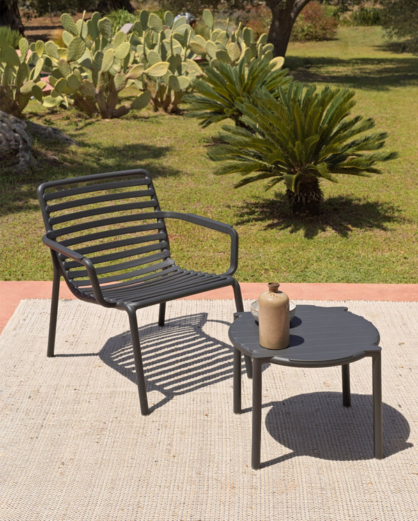 Sillón con apoyabrazos Doga Relax Nardi Italia color grafito — vista de ambientación en terraza con mesa auxiliar redonda doga, jardín con cactus y palmera — bCasual